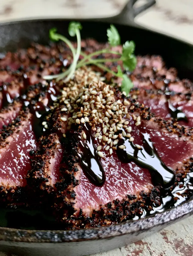 Blackened Balsamic Tuna Steaks with a Glossy Mahogany Glaze 2 Extreme close-up of thick sliced ahi tuna with a dark blackened crust and rare pink center. (Blackened Balsamic Tuna Steaks)