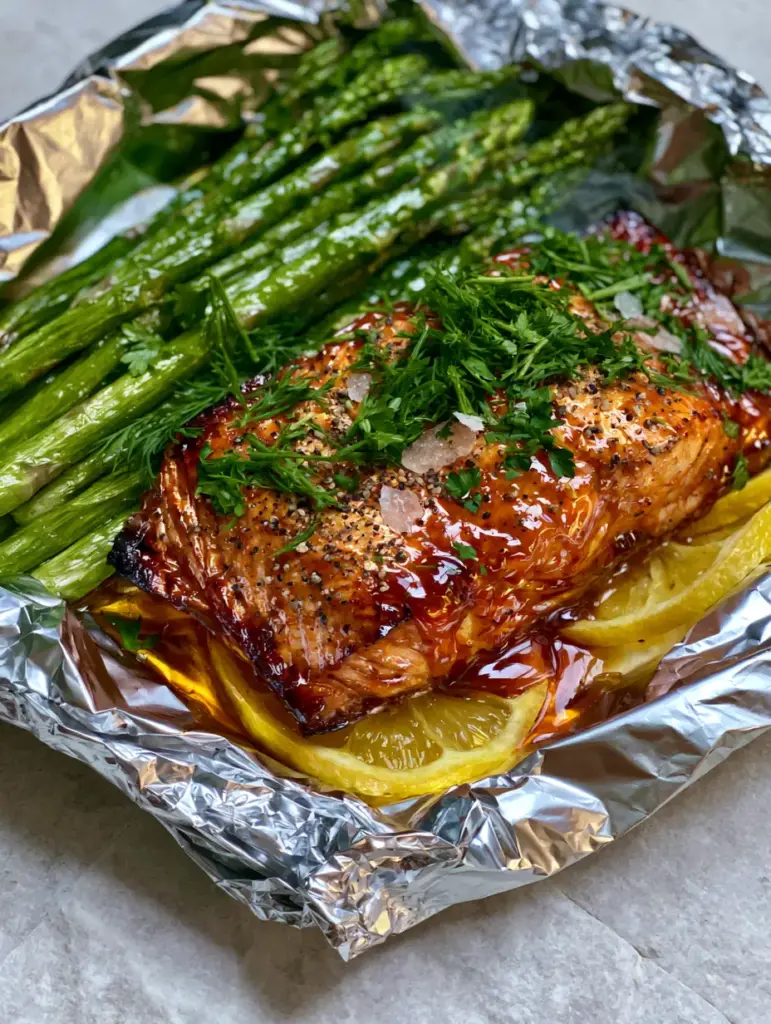 Foil Packet Recipes: The Ultimate Honey Garlic Glazed Salmon and Asparagus 1 Handheld photo style of a salmon foil packet with fresh dill and lemon slices.