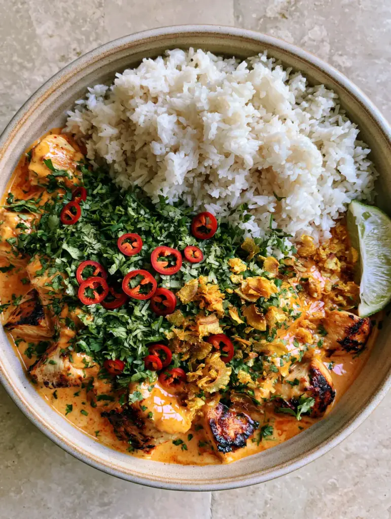 Full view of the Coconut Chicken Rice Bowl with cilantro, red chilies, and lime wedge garnish.