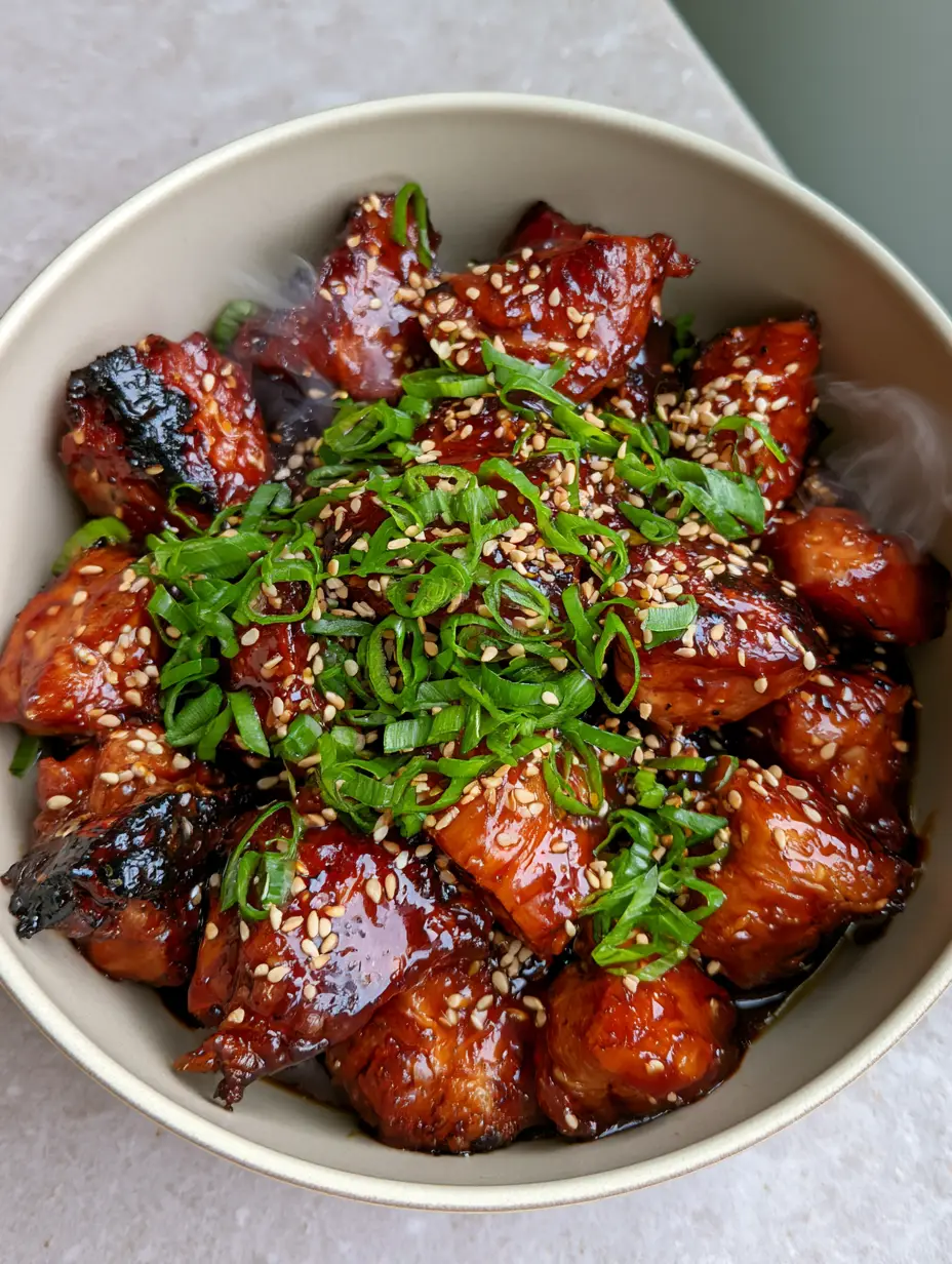 High-angle smartphone photo of glossy teriyaki chicken in a ceramic bowl with visible steam. (Teriyaki Chicken Recipe)