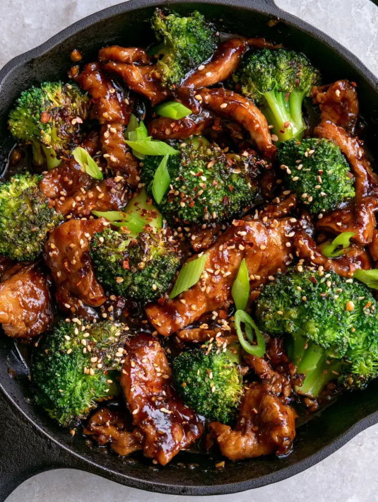 Chicken and broccoli recipe: The 15-Minute Secret to Velvety Poultry and Charred Emerald Florets 2 Top-down view of chicken and broccoli recipe in a cast iron skillet with visible ginger bits and sesame seeds.