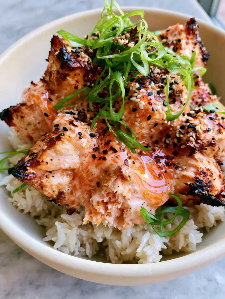 Bang Bang Salmon Recipe: Crispy Air-Fried Bites with Spicy Creamy Sauce 3 A handheld smartphone photo of crispy salmon cubes with charred edges smothered in glossy orange bang bang sauce on jasmine rice. (Bang Bang Salmon recipe)