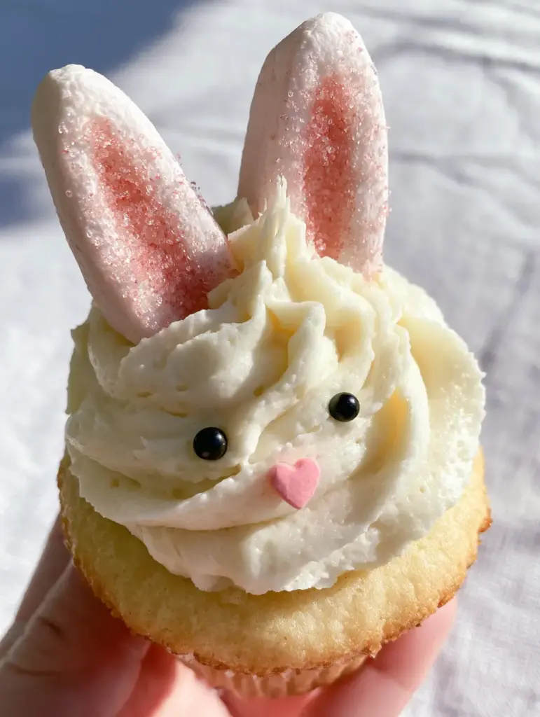 Bunny Cupcakes: The Ultimate Marshmallow Easter Dessert 1 Macro shot of Bunny Cupcakes showing the texture of the sparkling rose-pink sanding sugar and black pearl eyes.