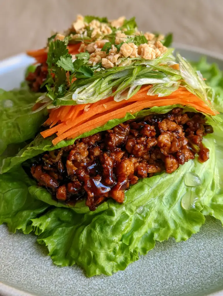 Extreme close-up of Thai Chicken Lettuce Wraps showing the dark amber hoisin glaze and bright orange carrots. (Thai Chicken Lettuce Wraps)