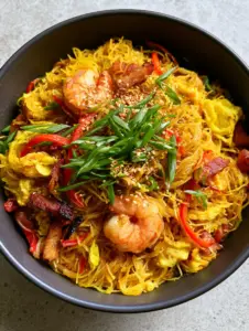 Top-down view of Singapore noodles showing charred pork slivers and fluffy egg ribbons.