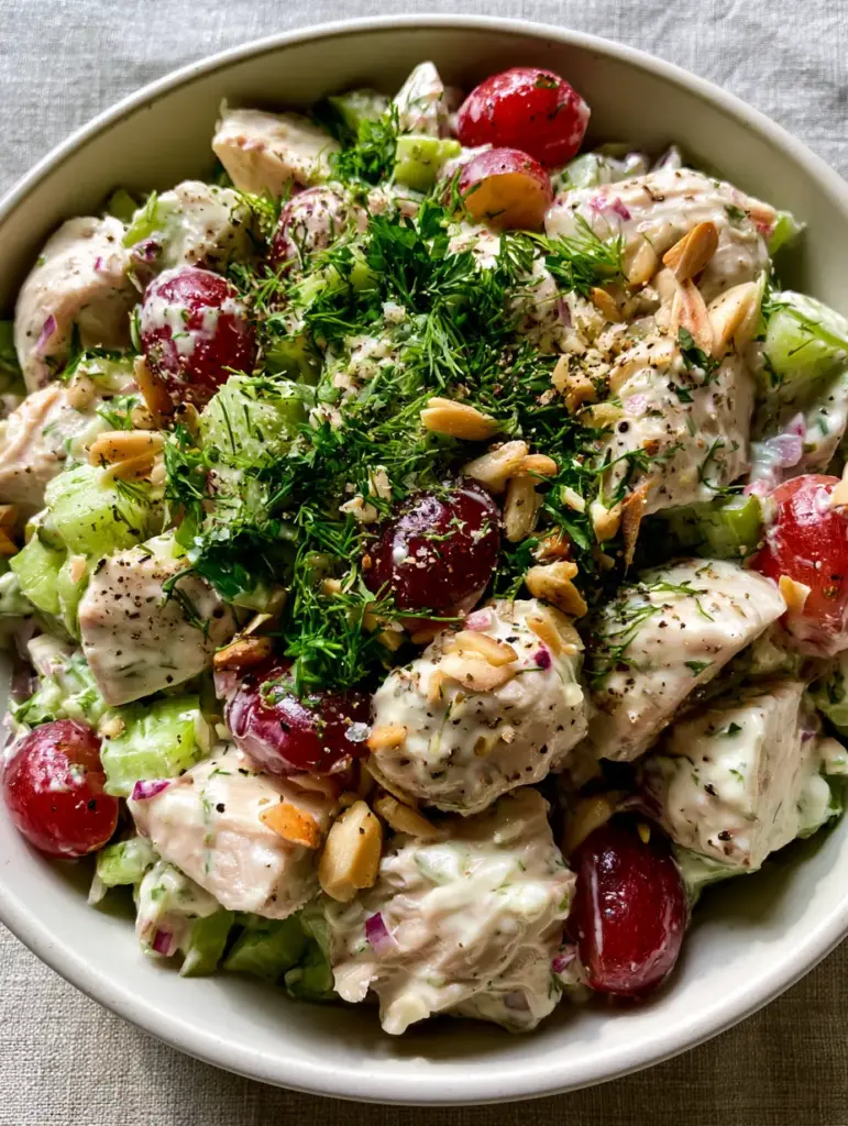 Close-up of crimson grapes and toasted almonds in a chicken salad recipe bowl.