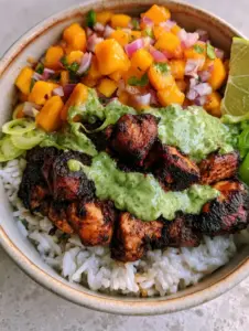 Macro view of charred jerk chicken breast cubes with a dark mahogany spice crust. (Jerk chicken bowl)