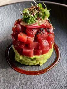 Close-up macro shot of diced ruby-red Ahi tuna for Nobu Tuna Tartare glistening with sesame oil.