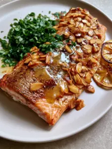 Close up of pan-seared rainbow trout fillet with golden-bronze crispy skin and flaky pink meat.