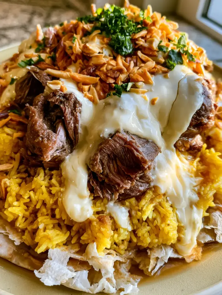 Handheld photo of Lamb Mansaf showing tender meat fibers and golden turmeric rice. (Mansaf recipe)